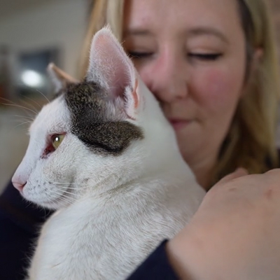 Calfornia King the cat being held by adopter